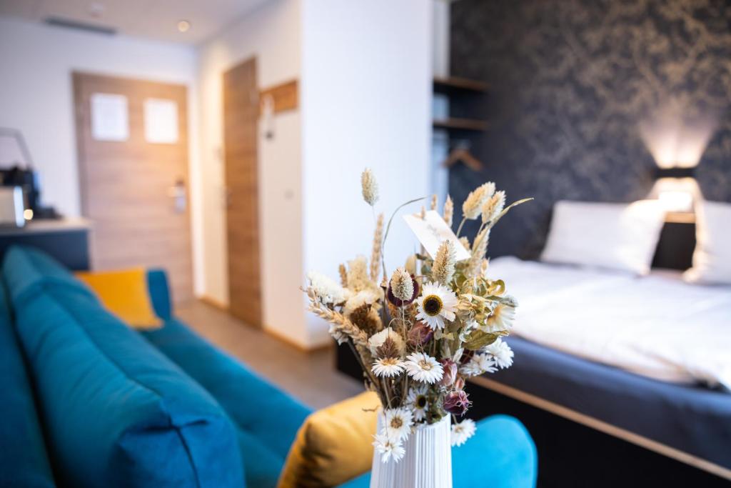 a living room with a blue couch and a vase with flowers at Motel Q in Jestetten