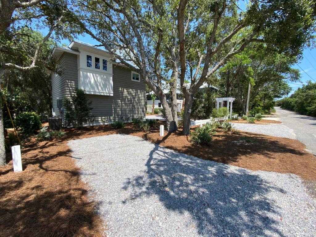 a house with a tree and a gravel driveway at Crystal Blue Persuasion in Santa Rosa Beach