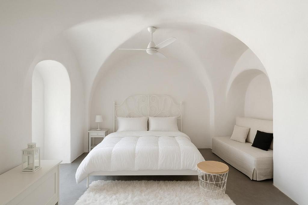 um quarto branco com uma cama branca e um sofá em Unique small stonehouse at Thira em Megalokhori