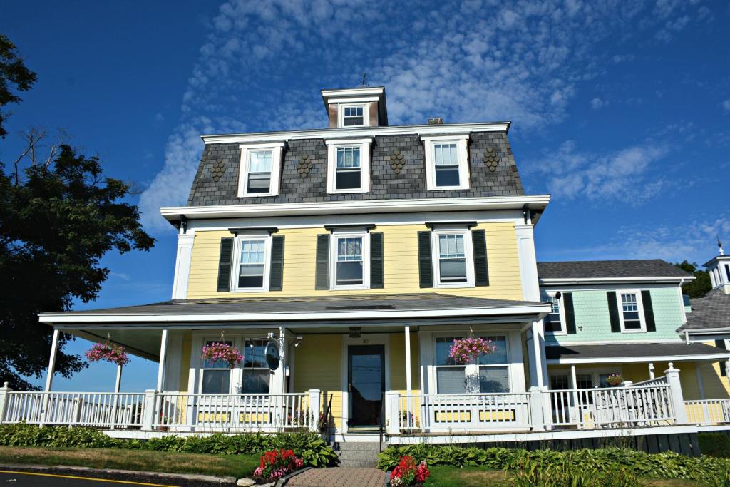 une grande maison jaune avec une véranda blanche dans l'établissement Harbor House Inn, à Boothbay Harbor