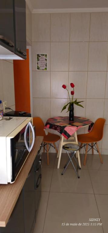 a kitchen with a table with red flowers on it at Apartamento Centro à 100 metros da Praça da Matriz in Boituva