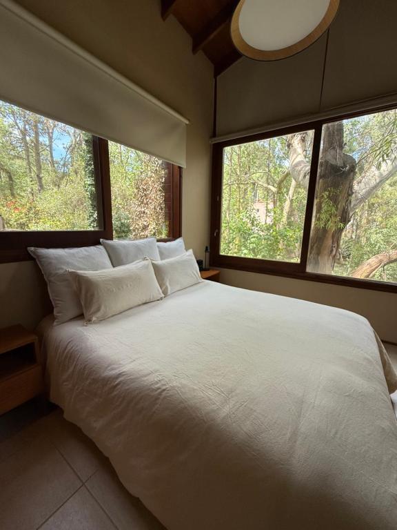 een slaapkamer met een groot wit bed met twee ramen bij Casa Azul in Mar de las Pampas