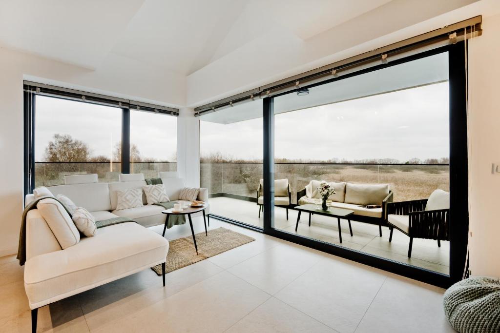 a living room with large windows and white furniture at BlueApart Jeżynowa Jastarnia in Jastarnia