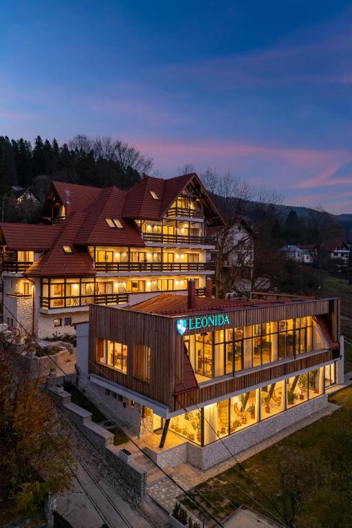 a large building with lights on in the evening at Pensiunea Leonida - RESORT LEONIDA in Poiana Ţapului