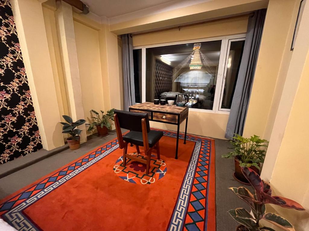 una habitación con una mesa y una silla y una ventana en Spacious Traditional Room with Boudha Stupa View, en Katmandú