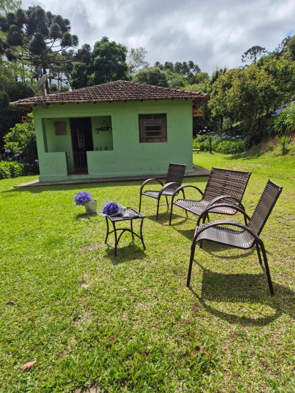 a group of chairs sitting in the grass in front of a house at Chalé 01 maritacas in Cunha