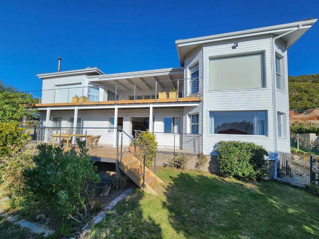 una grande casa bianca su una collina con un cortile di Living Lagoon Two Apartments a Brenton-on-Sea