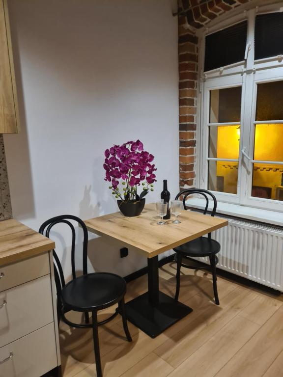 einen Tisch mit 2 Stühlen und eine Vase mit lila Blumen in der Unterkunft Piernikowy Strumyk in Toruń
