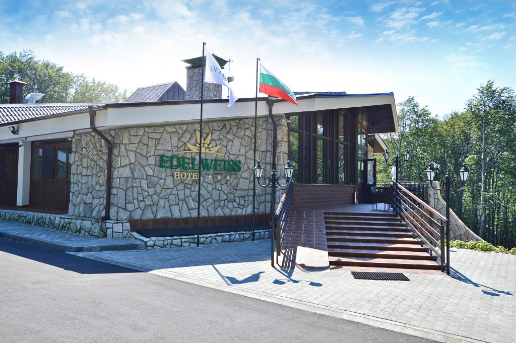 um edifício com bandeira e um edifício com escadas em Hotel Edelweiss em Shipka