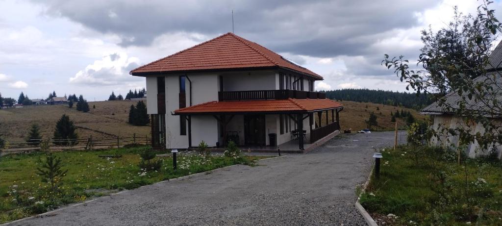 a small building with a red roof on a road at Pensiunea Bălcești Beliș Apuseni in Beliş