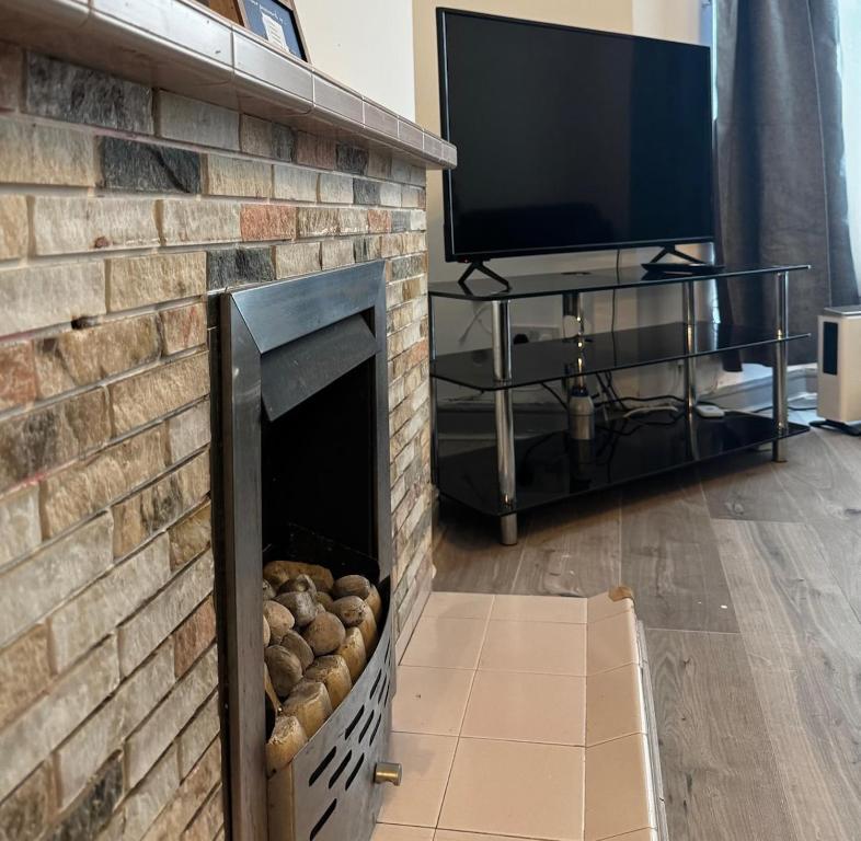 ein Wohnzimmer mit einem Kamin und einem Flachbild-TV in der Unterkunft A cozy, comfortable, calm house perfect for groups in Swansea