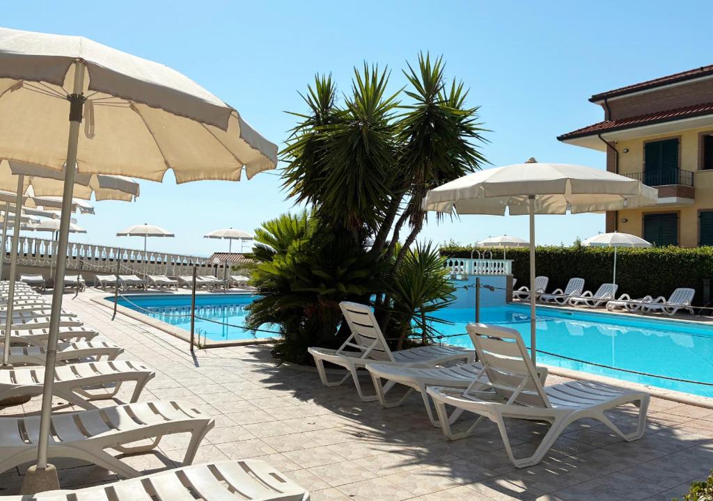 a pool with chairs and umbrellas next to a resort at Holihome Vascello B21 in Tortoreto Lido