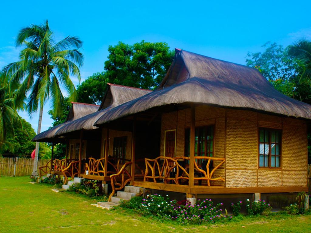 una pequeña casa con techo de paja y sillas en Jurisu Resort, en San Vicente