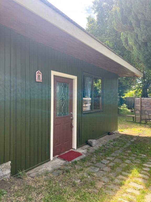 ein grünes Haus mit roter Tür und Terrasse in der Unterkunft Casa Alma in Pucón