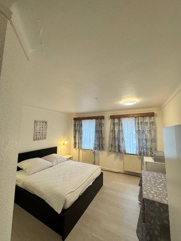 a bedroom with a large bed and two windows at Landhotel Waldschänke in Berlin