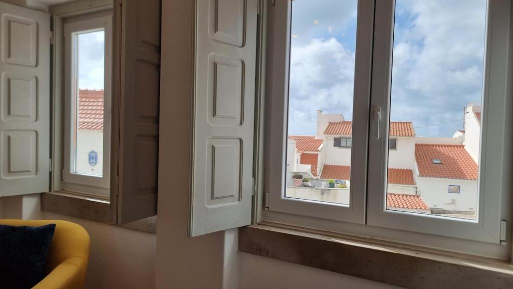 twee ramen in een kamer met uitzicht op een gebouw bij Fonte do Norte in Ericeira