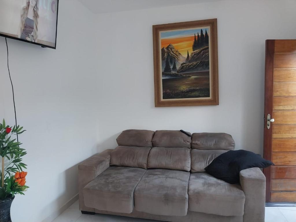 a couch in a living room with a picture on the wall at Apartamento na praia 2 qt com quintal e churrasqueira in Itanhaém