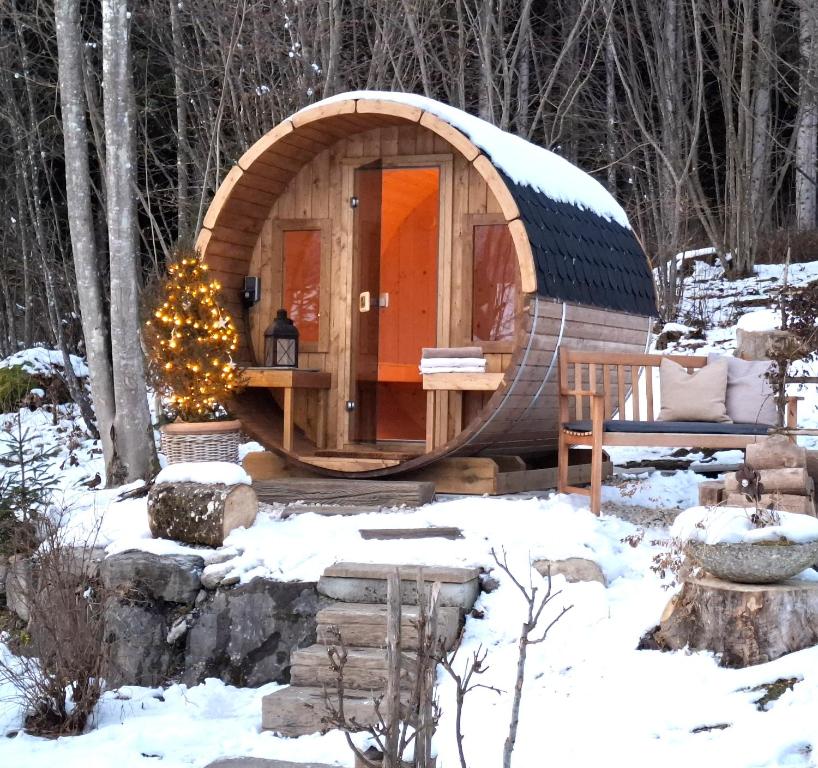 阿布特瑙Ferienhaus Lechner am Waldrand mit Sauna, Bergblick und Naturgarten"的雪地森林里一座木制鬣蜥小屋