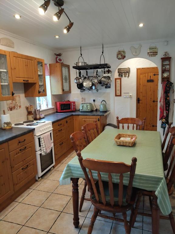 a kitchen with a table and chairs and a kitchen with a stove at Carnowen Cottage in Ringsend