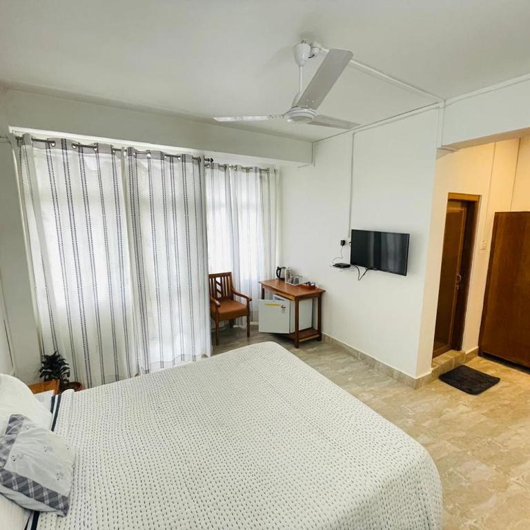 a bedroom with a bed and a desk and a television at Arara Group Hotel Majuli in Majuli