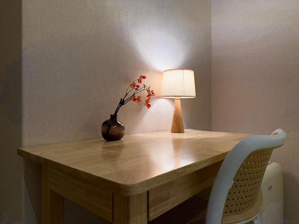 una mesa con una lámpara y un jarrón con flores en 小暮行旅 Twilie Stay, en Yilan City