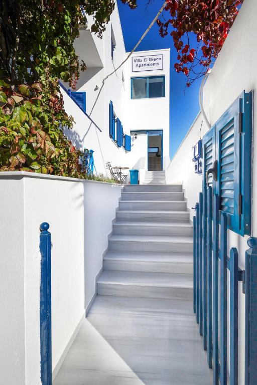 a staircase leading up to a white building with blue doors at Villa El Greco Apartments in Agia Marina Aegina