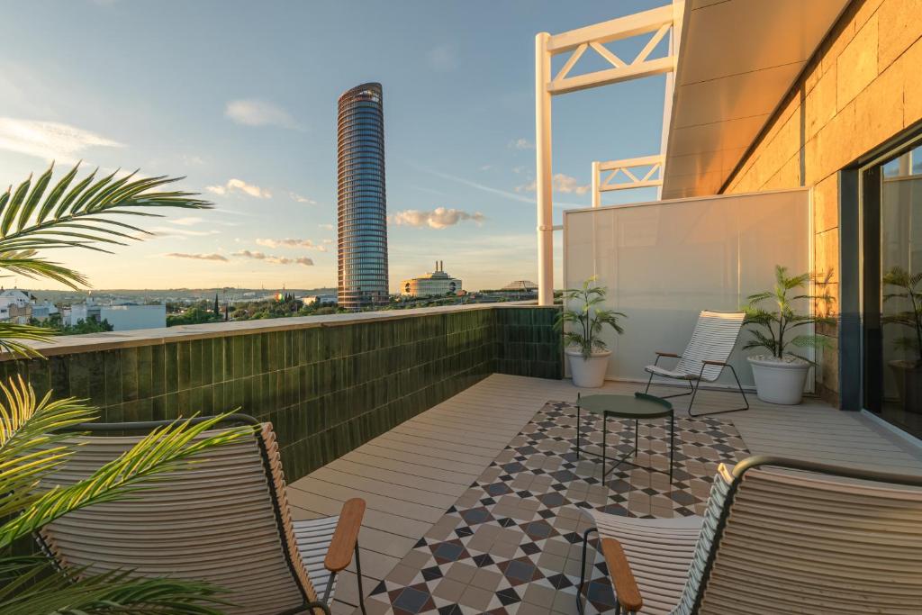 ein Balkon mit Stühlen und einem Tisch auf einem Gebäude in der Unterkunft Ribera de Triana Hotel in Sevilla