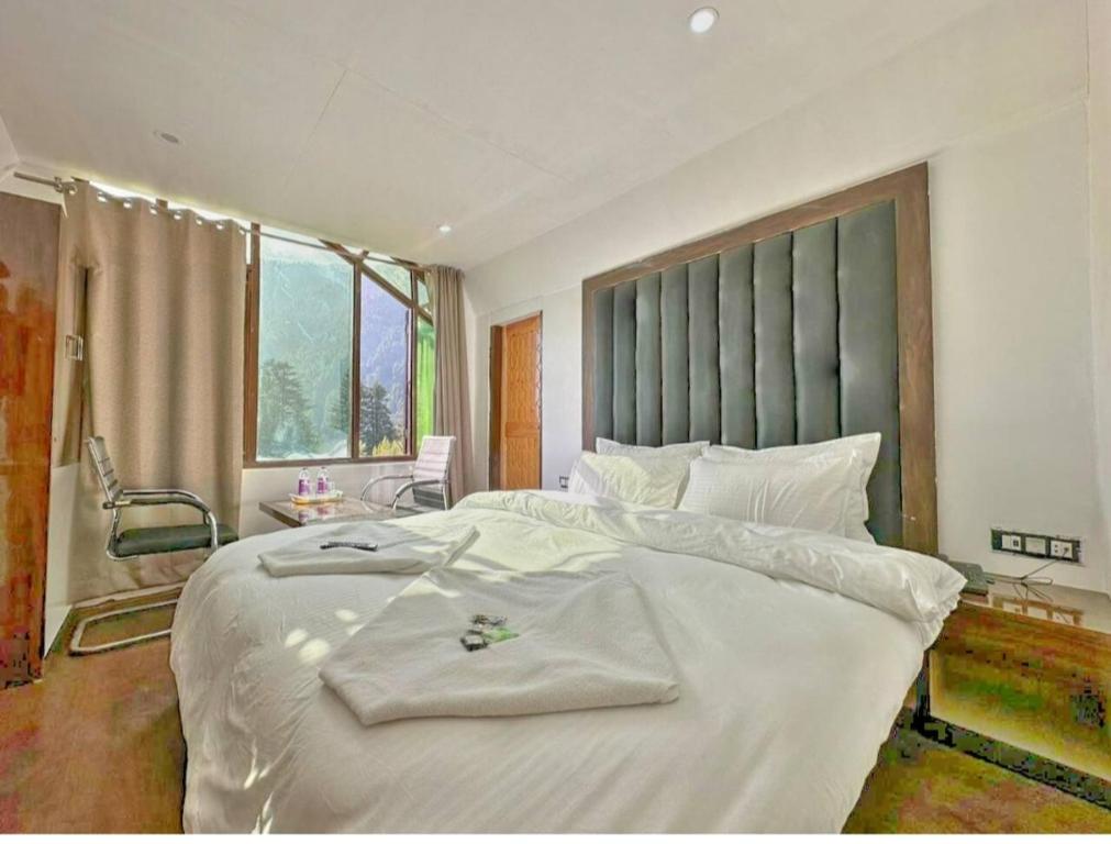 een slaapkamer met een groot wit bed en een groot raam bij Hotel Hills Heaven in Pahalgām