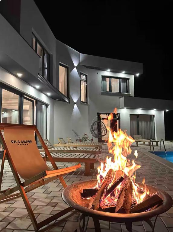 a fire pit in front of a house with a chair at Vila Amore Sarajevo Bjelasnica 