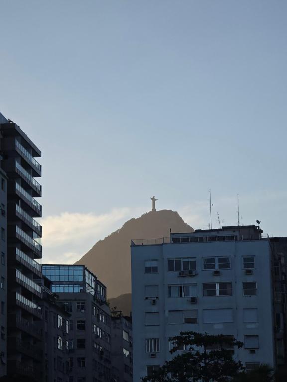 a cross on top of a mountain behind some buildings at Apto Gatinho in Rio de Janeiro