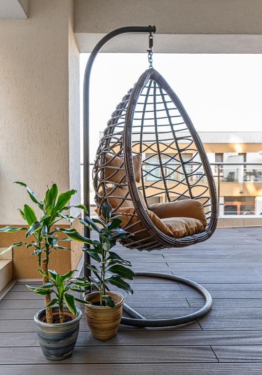 a hanging chair on a balcony with potted plants at Luxury 2BR Apartment - Amazing Terrace in Braşov