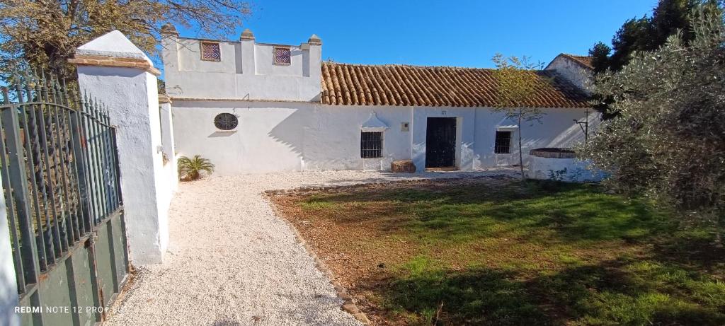 ein weißes Haus mit einem Zaun und einem Hof in der Unterkunft El Cortijillo de la Marquesa in Villar