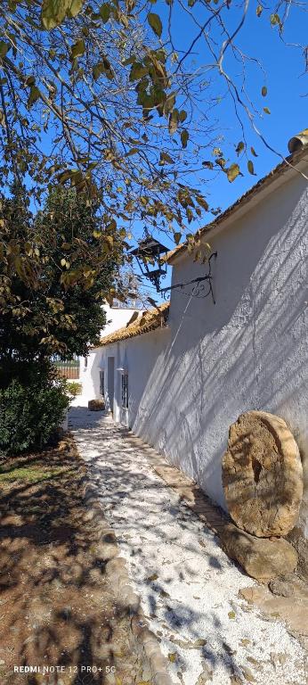 a white wall and a sidewalk next to a building at El Cortijillo de la Marquesa in Villar
