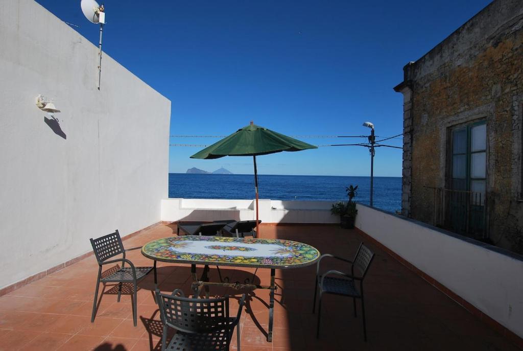 a patio with a table and chairs and an umbrella at Oasi 2 terrace overlooking the sea in Canneto in Canneto - Lipari