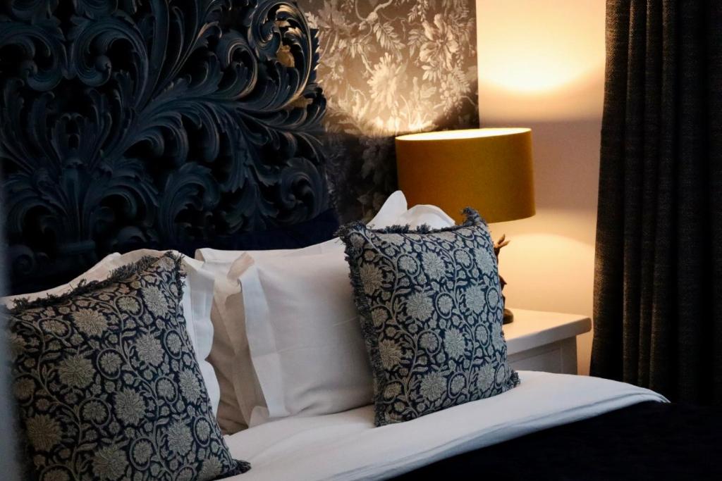 利明顿THE KNIGHTWOOD OAK a Luxury King Size Bed - En-Suite Space - LYMINGTON NEW FOREST with Totally Private Entrance - Key Box entry - Free Parking & Private Outdoor Seating Area - Town ,Shops , Pubs & Solent Way Walking Distance & Complimentary Breakfast的一间卧室配有带枕头的床铺和黑色床头板