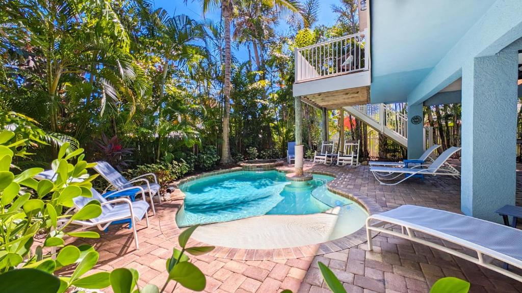 ein Swimmingpool mit Stühlen und ein Haus in der Unterkunft Beach Breezes in Anna Maria Island