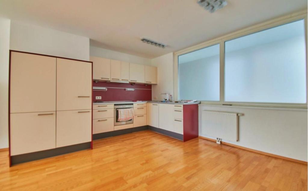 una cocina vacía con armarios blancos y una ventana grande en 2 Minunten neben kaiserlichem Park, Zentrumnähe, en Viena