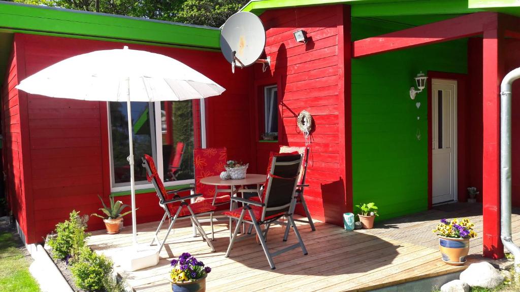 ein rot-grünes Haus mit einem Tisch und einem Sonnenschirm in der Unterkunft Ferienhaus Sonneneck mit Motorboot und Kanu in Basedow