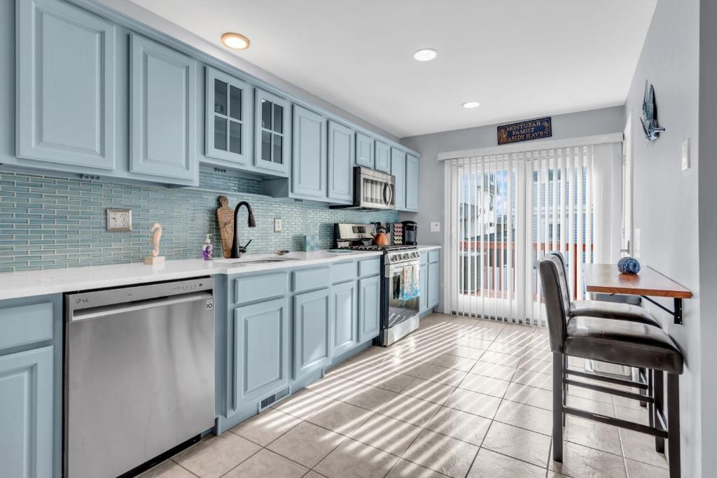 a kitchen with white cabinets and a table and a chair at Seaside Park Beach Home 3BR w Deck Peloton Parking 6 Beach Passes in Seaside Park