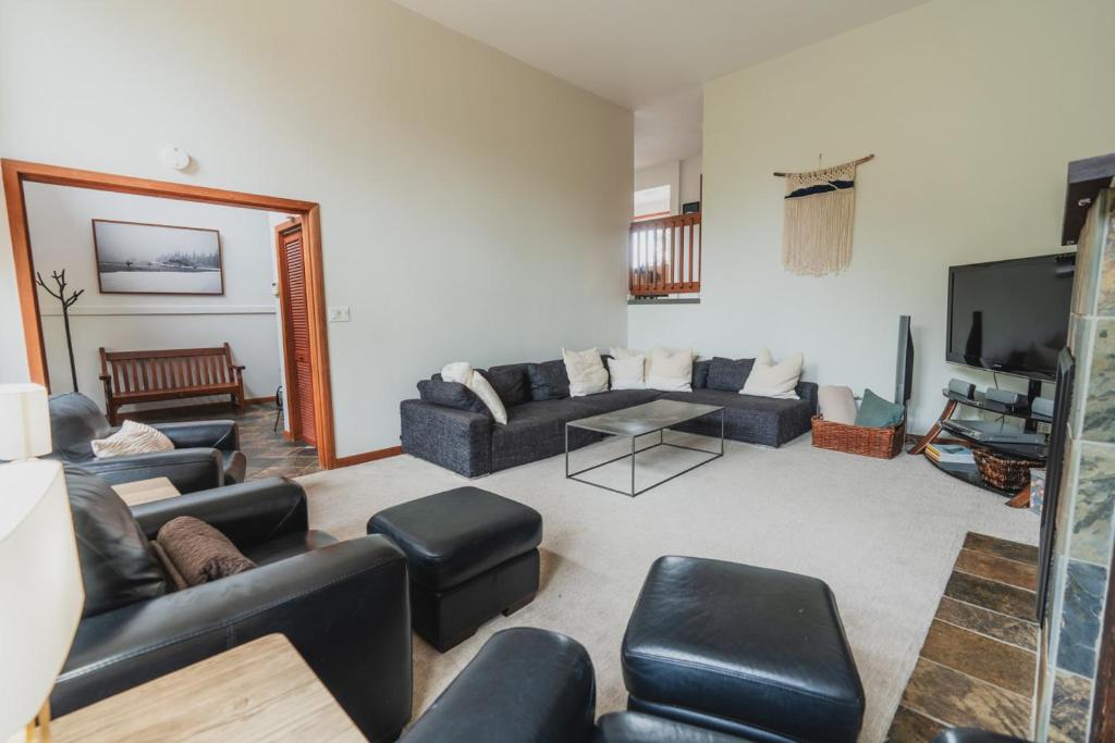 ein Wohnzimmer mit Sofas und einem Flachbildfernseher in der Unterkunft Chesterman on the Point - Beachfront in Tofino