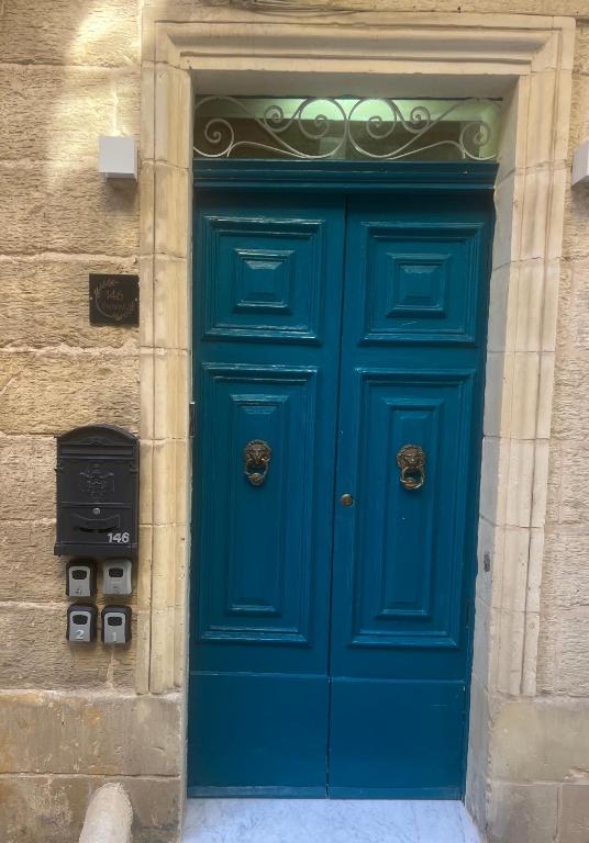 eine blaue Tür an einem Steingebäude mit einer Telefonzelle in der Unterkunft Phi Home Bormla in Vittoriosa