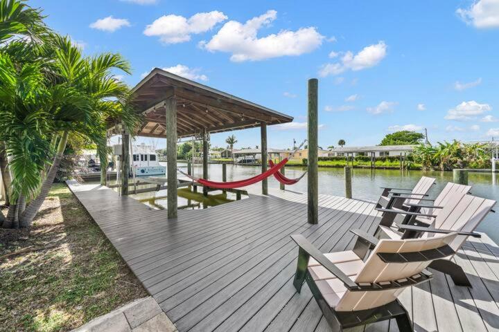a wooden deck with chairs and a red rope at Manatee Cove Waterfront Home w Dock Pool in Cocoa Beach