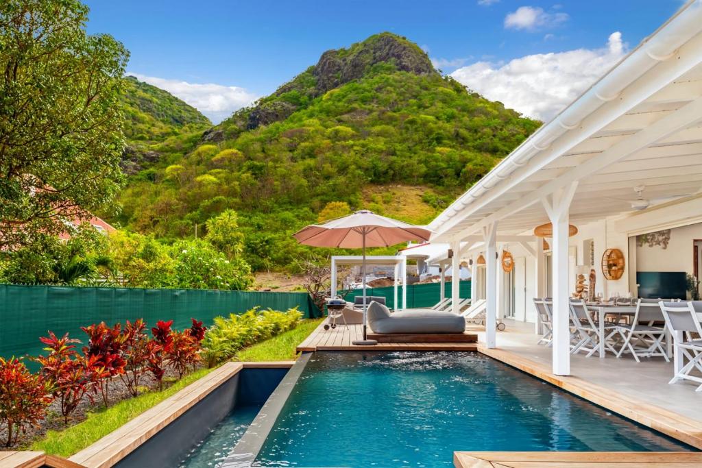 a house with a swimming pool and mountains in the background at Villa Bohème in Terre-de-Haut