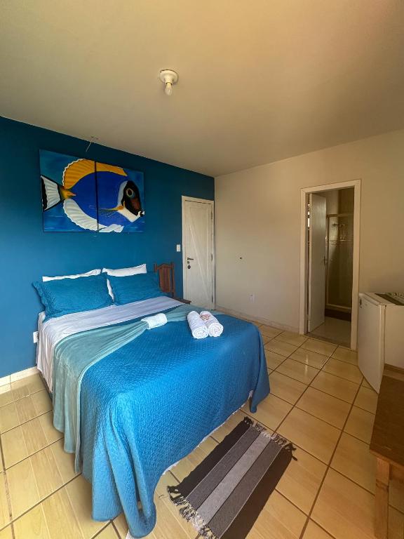 a blue bedroom with a bed with a fish painting on the wall at Buena Onda Suites in Abraão