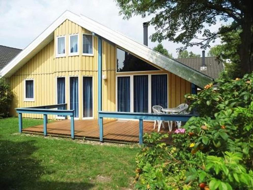 a yellow house with a deck with a table at exklusives skandinavisches Ferienhaus in Granzow