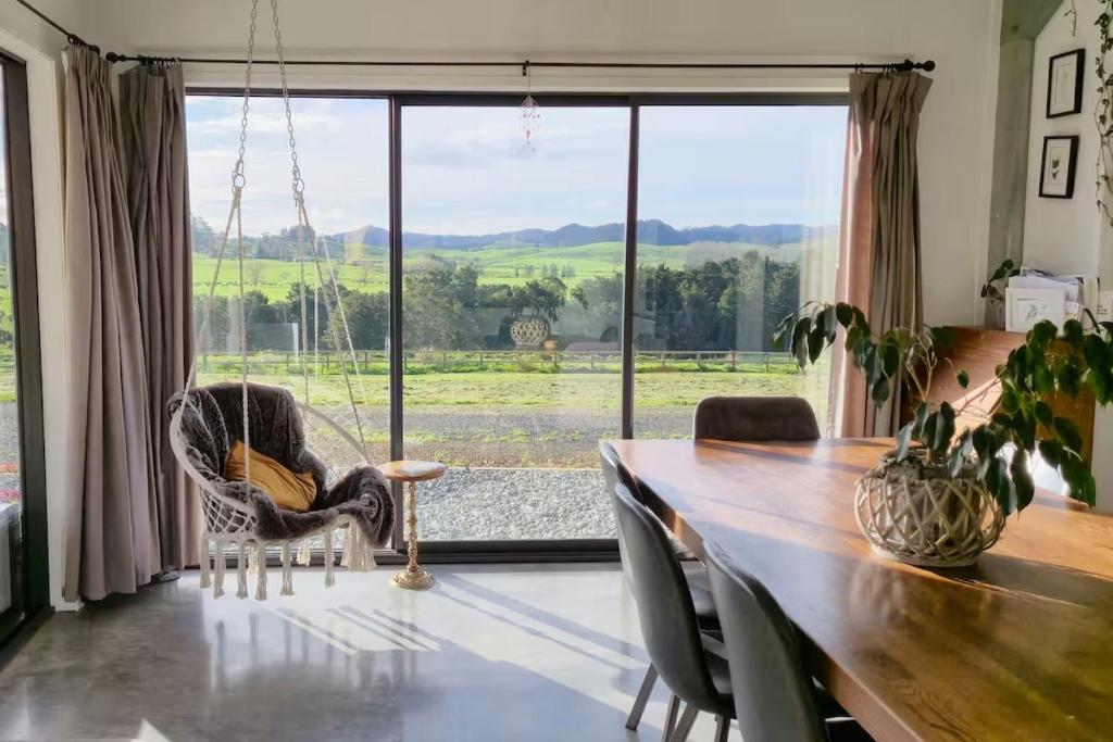 a dining room with a table and a large window at Spacious Valley Views Near City & Coast in Whangarei