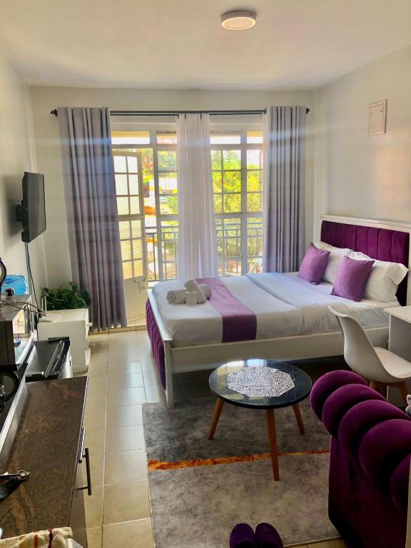 a bedroom with a large bed and a living room at Belaire BnB Ruaka 3 in Ruaka