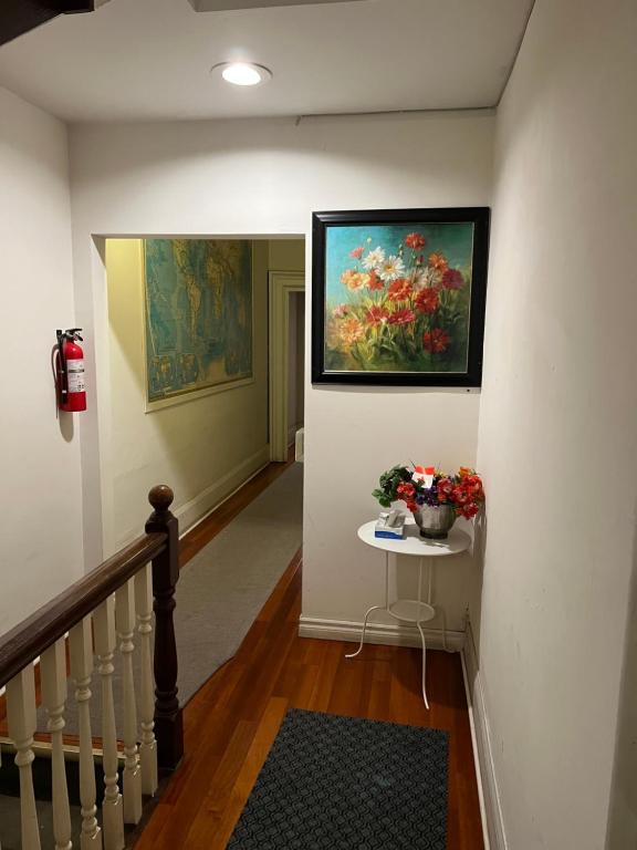 a hallway with a painting and a table with flowers at Klaus Guesthouse in Toronto