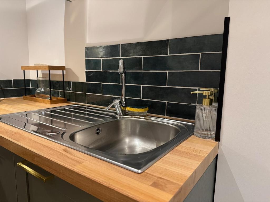 杜埃La Location des géants - Appartement avec terrasse的厨房里的一个不锈钢水槽,有黑色的瓷砖