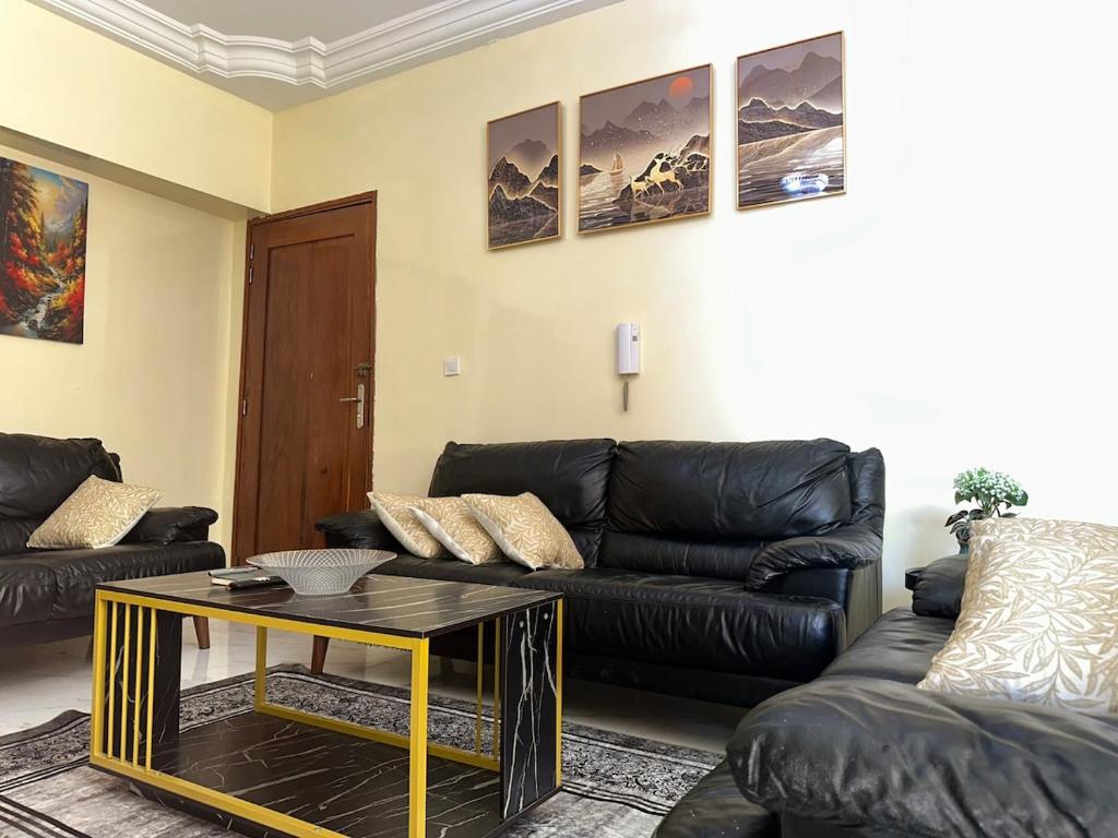 Una sala de estar con un sofá de cuero negro y una mesa. en Express at home, en Dakar